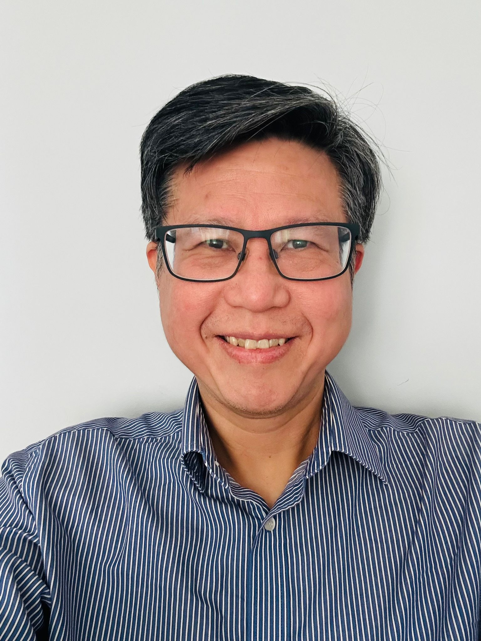 A man wearing glasses and a stripy shirt smiling