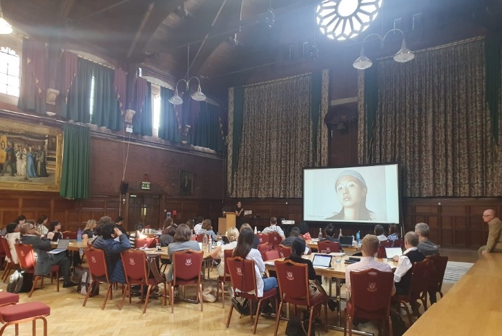 Students sat around tables watching a presentation at Homerton College