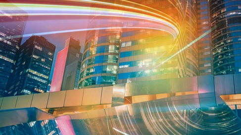 Modern city skyline with illuminated office buildings and dynamic light trails representing innovation, digital transformation, future markets and sustainable economic growth.