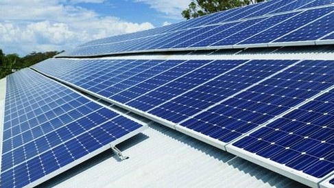 Solar photovoltaic panels mounted on a rooftop, generating renewable electricity from sunlight under a partly cloudy sky.