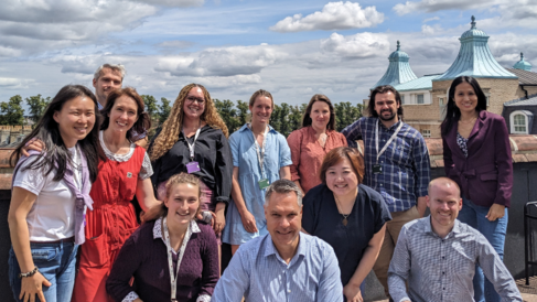 It's a sunny day in Cambridge, and a team of people are smiling at a camera, whilst stood on a on a roof top terrace. There's a mix of men and women from all different backgrounds, it's the Canopy team from CISL.