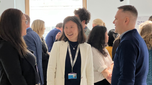 An image of 3 people at a Canopy event smiling and socialising with a crowd of people behind them. Taken from within the Entopia building at CISL.  