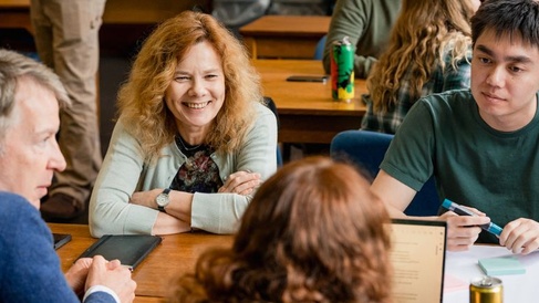 Four students sat around a table smiling. 