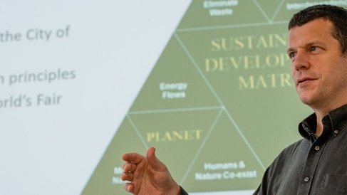 Tim Forman stood in front of a presentation with a triangle behind him. 