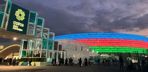 COP29 venue at stadium in Baku, lit up at night in Azerbaijan colours