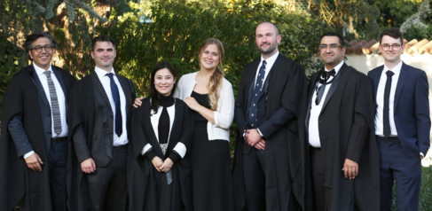 A group of students wearing formal wear and robes 
