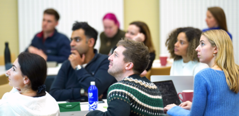 A group of students looking off camera towards a presentation