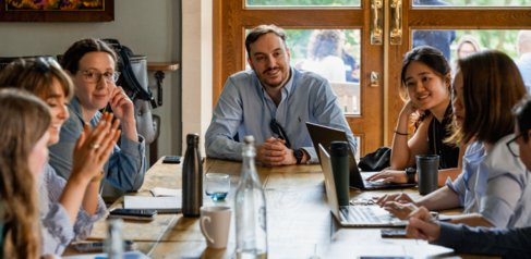 A group of students chatting and working around a table