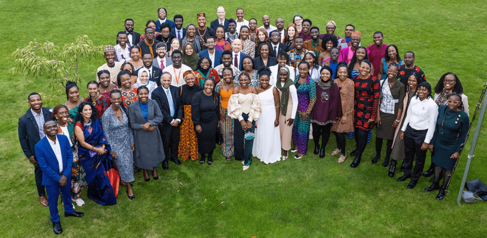 Group photograph of many happy delegates in a semicircle smiling at the camera on a green lawn 
