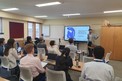 Students sat in a classroom setting with the lecturer Steve Evans presenting next to a screen