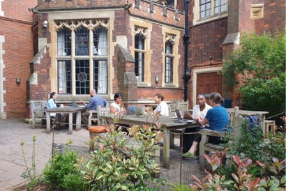 Students sat outside with their supervisors at on a patio area with wooden furniture
