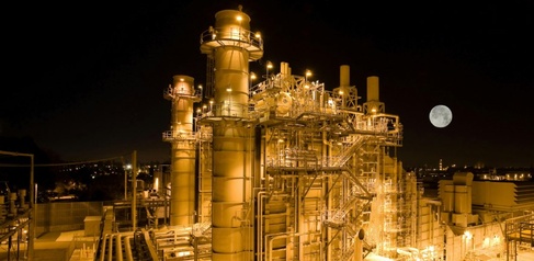 Natural gas plant lit up at night with moon low in sky