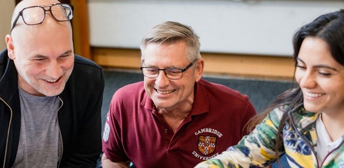 Three students looking at a laptop screen off camera and smiling