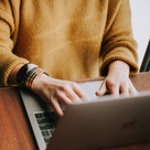 Arms and hands of a woman typing on laptop