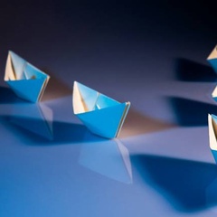 Paper boats forming the letter V (Victory)