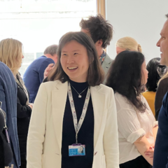 An image of 3 people at a Canopy event smiling and socialising with a crowd of people behind them. Taken from within the Entopia building at CISL.  