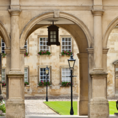 A photo of one of the Cambridge colleges with some arches, parked bicycles and a quad of grass in the background