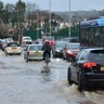 Vehicles, a bus and a cyclist travelling through a flooded urban street, illustrating the impacts of extreme weather and flood risk on transport infrastructure.