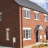 Image of a red brick semi detached new build house with coach house style houses behind