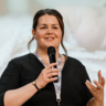 Emma Fromberg stood in front of a presentation with a microphone in her hand