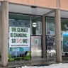 Image of a building with three large glass windows with posters stuck to the windows