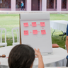 Postgraduate students working together around a board with sticky notes