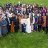 Group photograph of many happy delegates in a semicircle smiling at the camera on a green lawn 