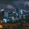 Cityscape at night with flashes of lightning over skyscrapers
