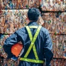 Worker standing in front of bales of plastic. Photo by Adobe Stock