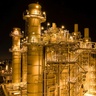 Natural gas plant lit up at night with moon low in sky