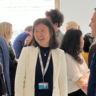 An image of 3 people at a Canopy event smiling and socialising with a crowd of people behind them. Taken from within the Entopia building at CISL.  