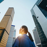 Woman gazes at tall build as the sun sets behind her