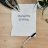 Desk with books, stationary and a notepad that reads 'marketing strategy'