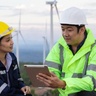 One female and one man working in a wind farm, engaged in discussion.