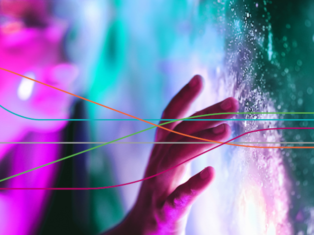 Close-up of a hand touching a brightly lit, textured surface with glowing pink and teal lights in the background, overlaid by several thin, multicoloured curved lines.