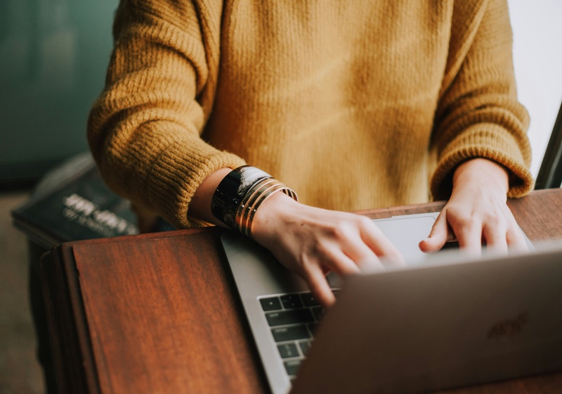 Arms and hands of a woman typing on laptop