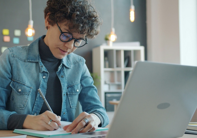 Person sitting in front of a laptop. Studying and writing