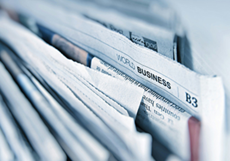 Stack of business newspapers and financial publications, representing sustainability news, market insights, corporate responsibility and global business trends.
