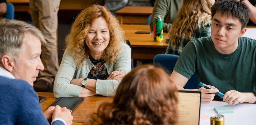 Four students sat around a table smiling. 