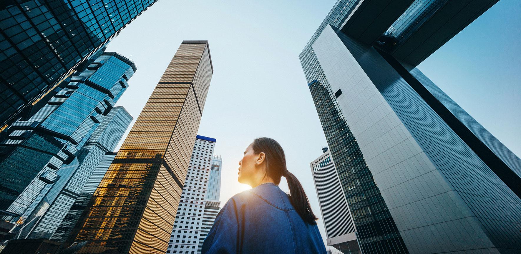 Woman gazes at tall build as the sun sets behind her