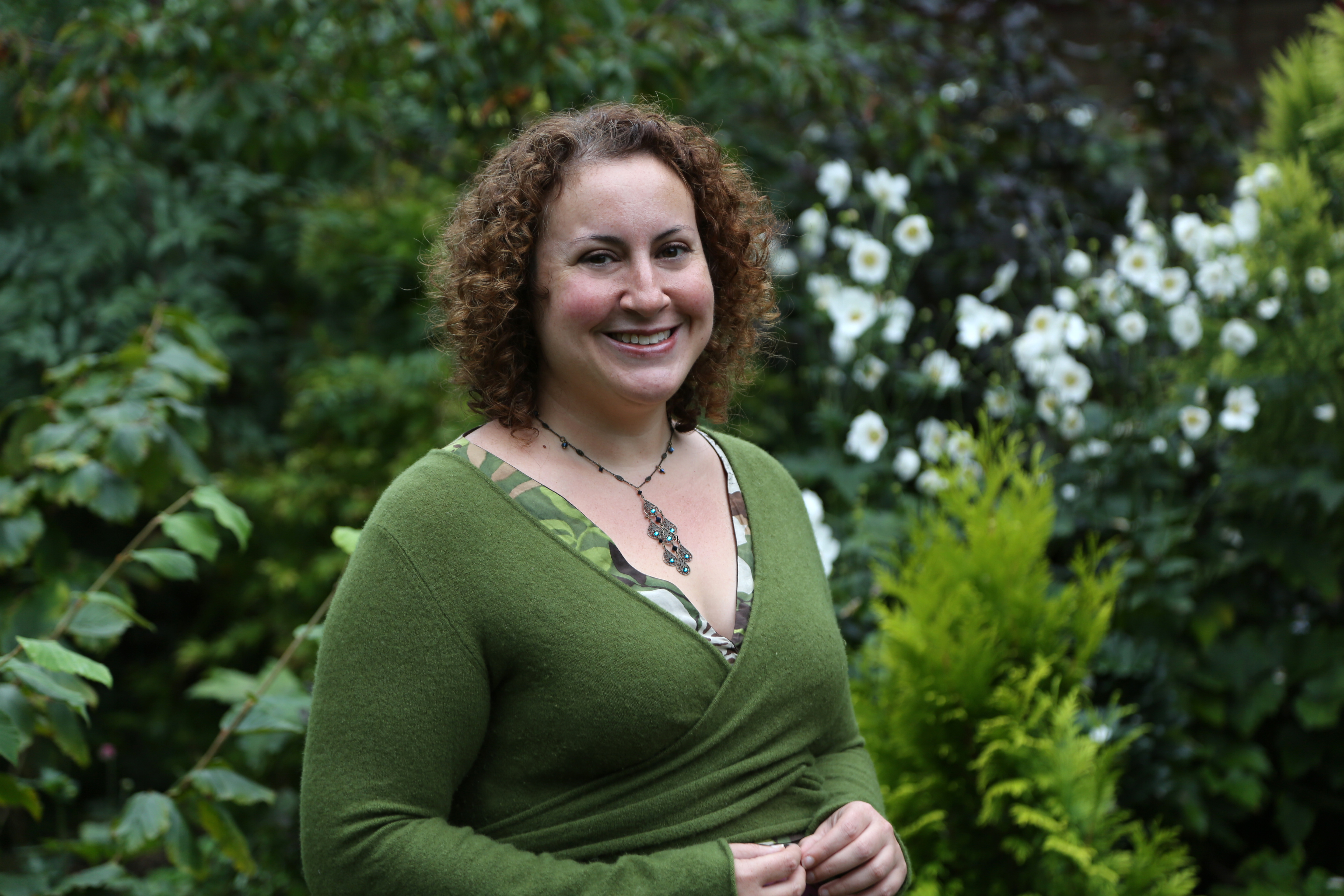 Dr Kayla Friedman standing in front of a green garden background
