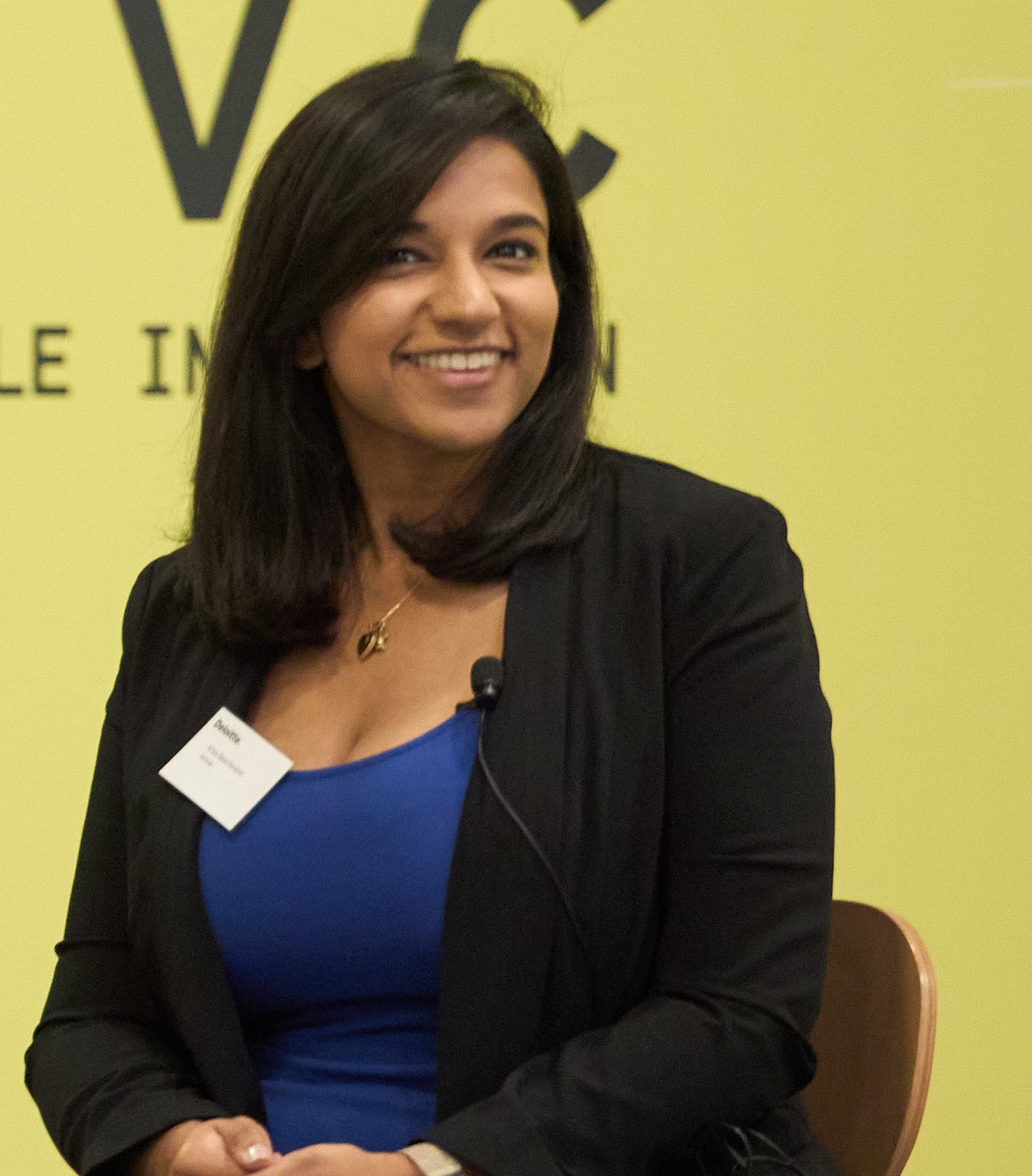 Image of Kripa Balachandran smiling in front of a yellow background